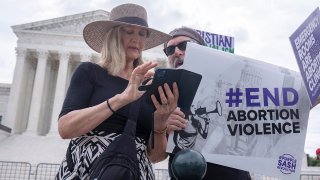 Katie Mahoney, left, and Rev. Patrick Mahoney, chief strategy officer for Stanton Healthcare, an Idaho-based pregnancy center that does not provide abortions, read the text of a Supreme Court decision outside the Supreme Court on Thursday, June 27, 2024, in Washington.