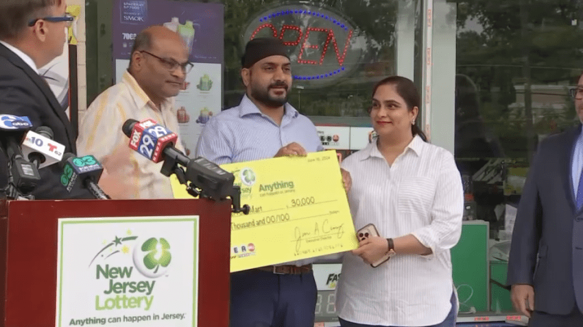 Tejinder Singh, his wife and a store worker hold up $30,000 check for selling Powerball jackpot ticket.