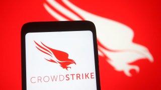 In this photo illustration, CrowdStrike logo of a U.S. cybersecurity technology company is seen on a smartphone and a pc screen.