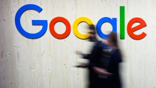 Trade fair visitors walk past a Google logo at the Google stand at Hannover Messe 2024. 