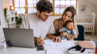 Young family with a baby boy going over finances at home.