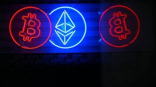 People walk past a neon sign advertising a Bitcoin and Ethereum crypto currency exchange in Warsaw, Poland on 19 May, 2024. 