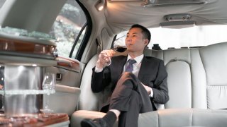 Asian businessman drinking in a luxury car.