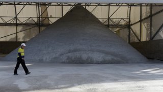 A worker walks past a pile of lithium ore at a Talison Lithium Ltd. site, a joint venture between Tianqi Lithium Corp. and Albemarle Corp., in Greenbushes, Australia.