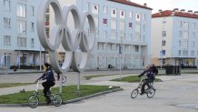 Athletes cycle past the Olympic rings