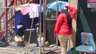 An outreach worker talks to a homeless woman ensconced in a makeshift shelter.