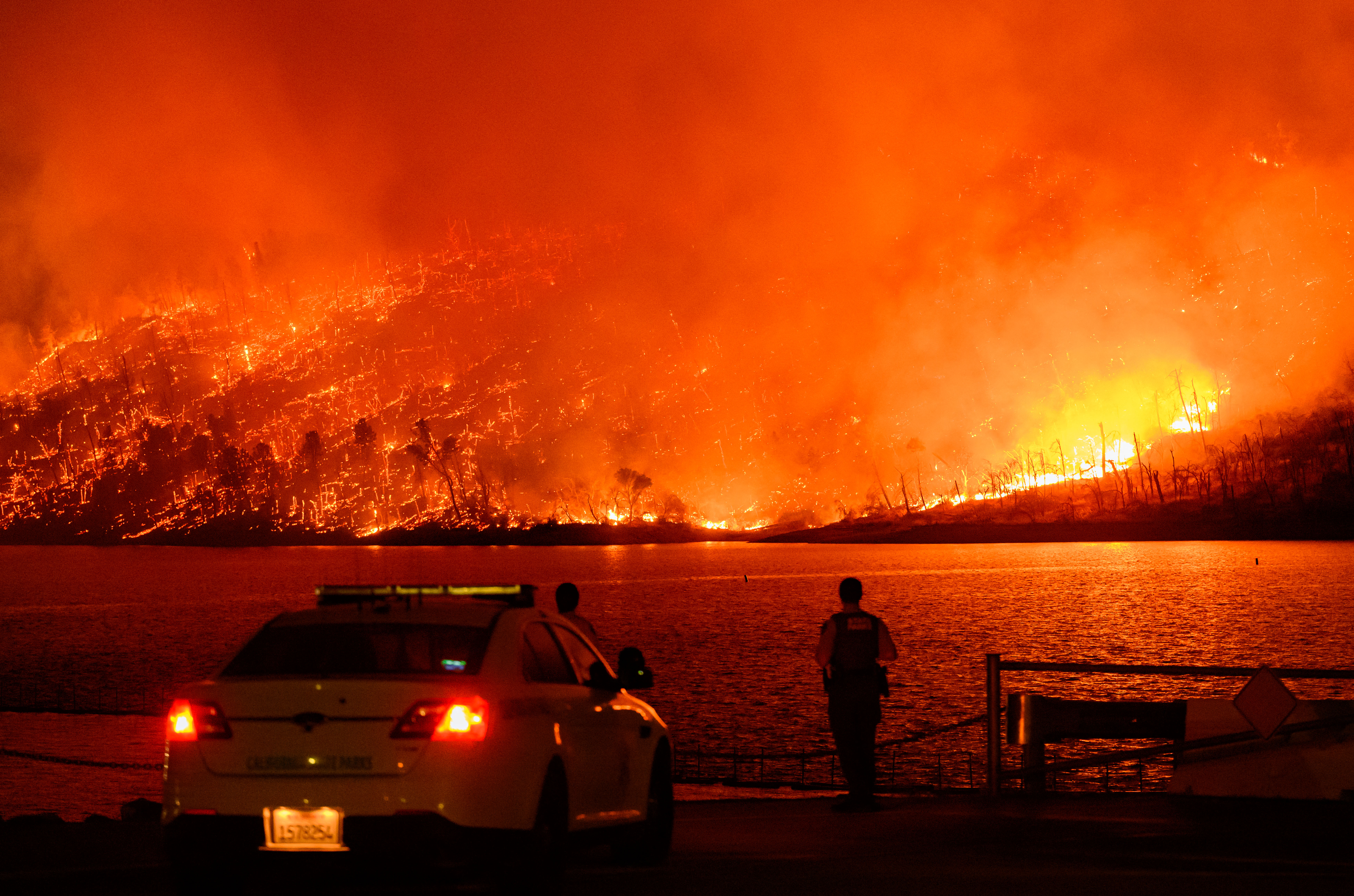 Law enforcement members watch as the Thompson fire burns over Lake Oroville in Oroville, California on July 2, 2024.