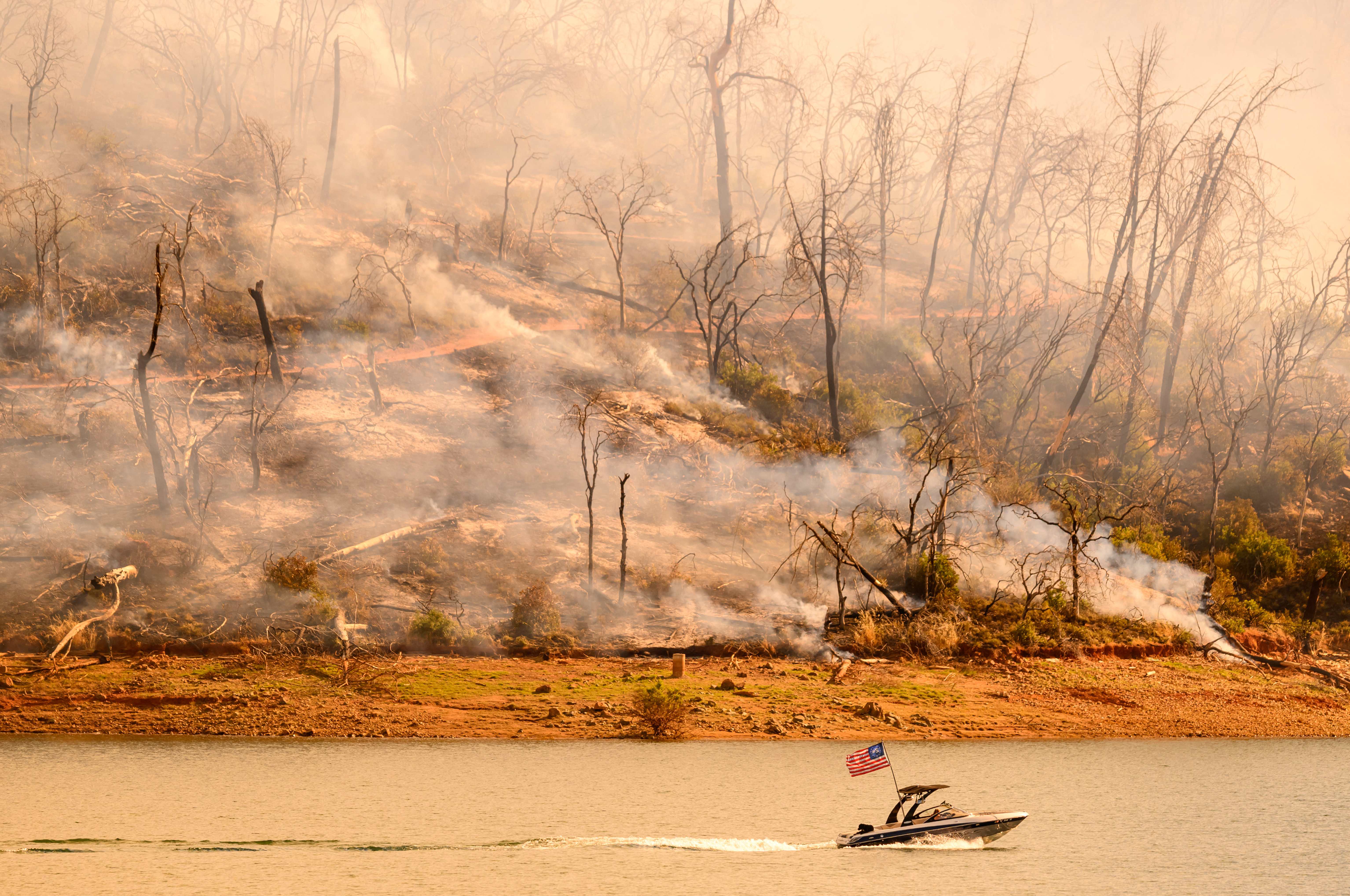 A boat moves along Lake Oroville as the Thompson fire continues to burn in Oroville, California on July 3, 2024.