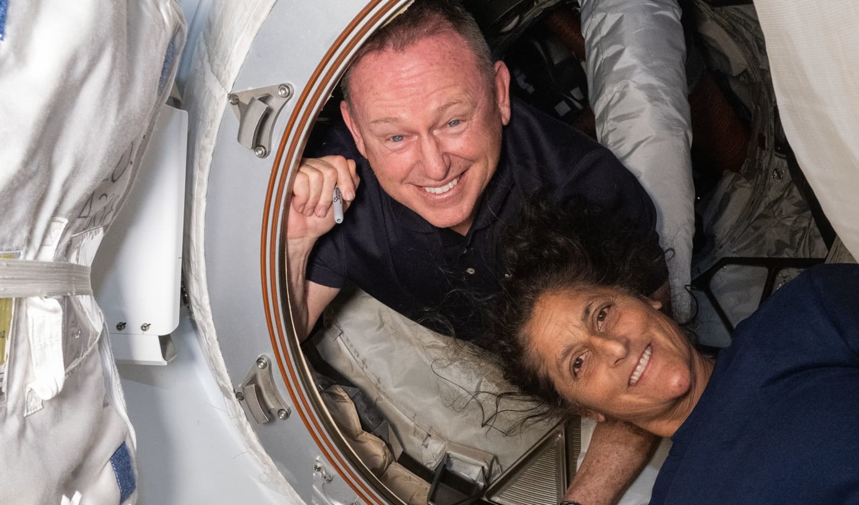 NASA astronauts Butch Wilmore, left, and Suni Williams pose inside the hatch connecting Boeing's Starliner to the International Space Station on