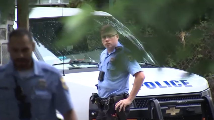 A Philadelphia police officer looks on as investigators recover a woman's body from behind a home in Philadelphia's Frankford neighborhood on Sunday Aug. 4, 2024.