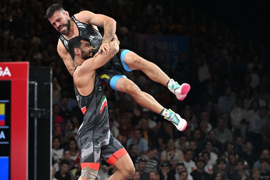 Iran's Alireza Mohmadipiani wrestles Colombia's Carlos Andres Munoz Jaramillo (blue) in their men's greco-roman 87kg wrestling early rounds match at the Champ-de-Mars Arena during the Paris 2024 Olympic Games, in Paris on August 7, 2024