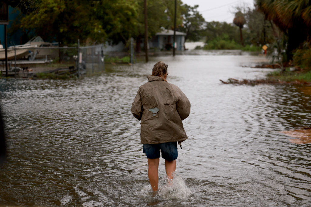 CEDAR KEY, FLORIDA - AUGUST 05:  A person walks through a flooded street caused by the rain and storm surge from Hurricane Debby on August 05, 2024, in Cedar Key, Florida. Hurricane Debby brings rain storms and high winds along Florida’s Big Bend area.  (Photo by Joe Raedle/Getty Images)