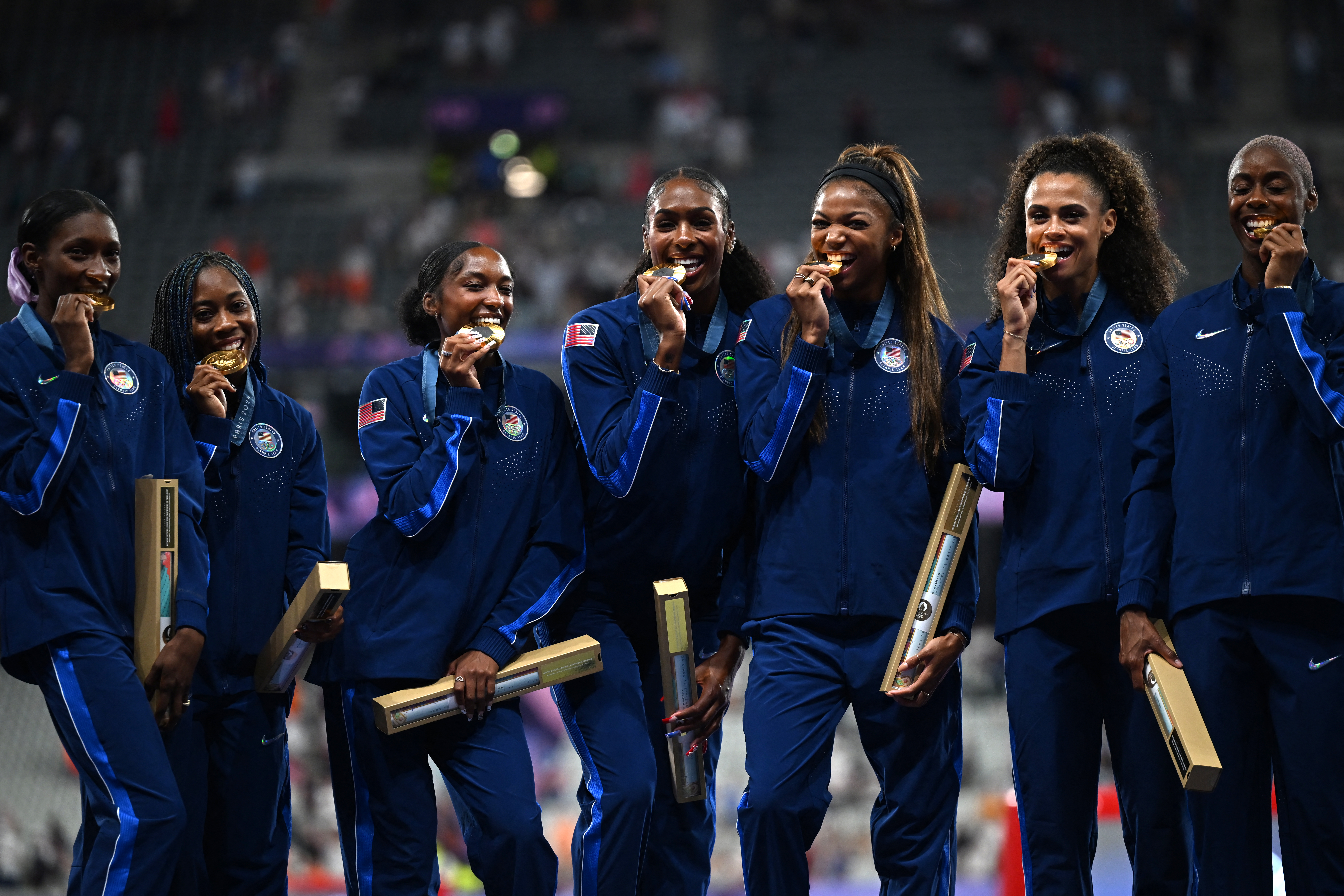 Gold medallists (from L) US' Quanera Hayes, Aaliyah Butler, Kaylyn Brown, Alexis Holmes, Gabriel Thomas, Sydney McLaughlin-Levrone and Shamier Little celebrate on the podium after competing in the women's 4X400m relay final of the athletics event during the Paris 2024 Olympic Games at Stade de France in Saint-Denis, north of Paris, on August 10, 2024. (Photo by MARTIN BERNETTI / AFP) (Photo by MARTIN BERNETTI/AFP via Getty Images)