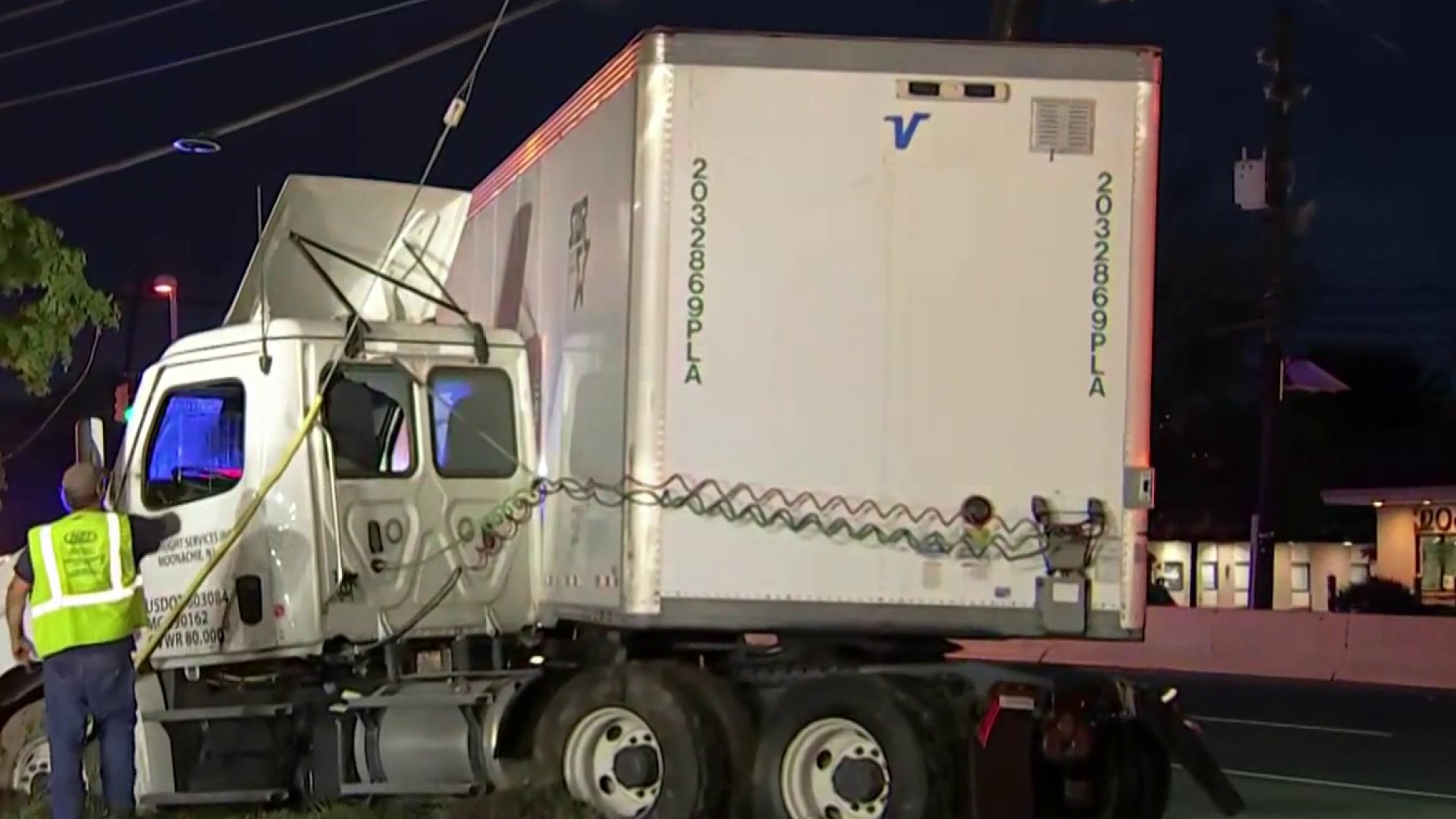 Jackknifed truck with worker in vest nearby