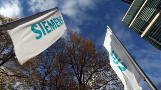 Flags with the word “Siemens” in front of the company’s headquarters.