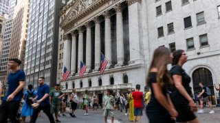 People walk through the financial district by the New York Stock Exchange (NYSE) on August 14, 2024, in New York City. 