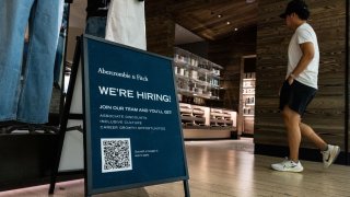 A shopper walks past a hiring sign displayed in front of Abercrombie & Fitch at the Tysons Corner Center mall on August 22, 2024 in Alexandria, Virginia. 