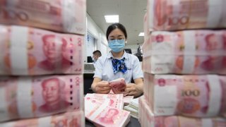 Staff members counting RMB cash deposited by customers in China’s Nantong city.