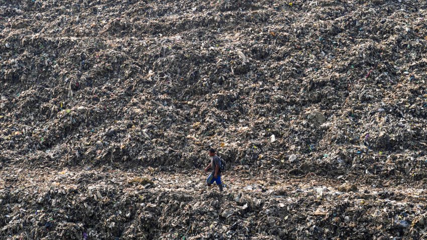 FILE - A wastepicker walks past on a pile of garbage at a landfill in Depok on the outskirts of Jakarta, Indonesia, May 10, 2024.