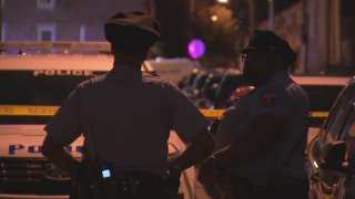 Philadelphia Police officers talk as they investigate along Judson Street in North Philadelphia after two men were hurt in a shooting early Sunday.