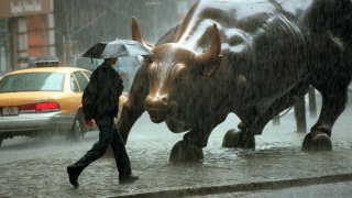 A pedestrian passes in front of a statue of a bull in the Wall Street area in New York City.