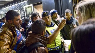 Police officer gestures at the railway station in Stockholm on September 12, 2015, after a train with migrants arrived from Malmo in southern Sweden. Back then, many newcomers hoped to reach Sweden which was seen as more welcoming and has a more generous asylum policy. 