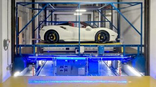 Robo-parkers whisk a Ferrari from a spot inside the automated parking system onto a lift.