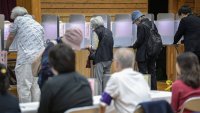 TOPSHOT – Officials look on as people vote during the general election at a polling station set up at a local school in Tokyo on October 27, 2024. Japan voted on October 27 in its tightest election in years, with new Prime Minister Shigeru Ishiba and his juggernaut Liberal Democratic Party facing potentially their worst result since 2009. (Photo by Richard A. Brooks / AFP) (Photo by RICHARD A. BROOKS/AFP via Getty Images)