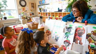 Preschool Executive Director Maria Isabel Ballivian, right, listens to her students on what characters of the TV show PAW Patrol they will vote for as their favorite character at the ACCA Child Development Center, Thursday, Sept. 19, 2024, in Annandale, Va. The students are getting foundational lessons on how to live in a democracy by allowing them to regularly vote on different things through out the day.