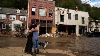 FILE – Resident Anne Schneider, right, hugs her friend Eddy Sampson as they survey damage left in the wake of Hurricane Helene, Oct. 1, 2024, in Marshall, N.C.