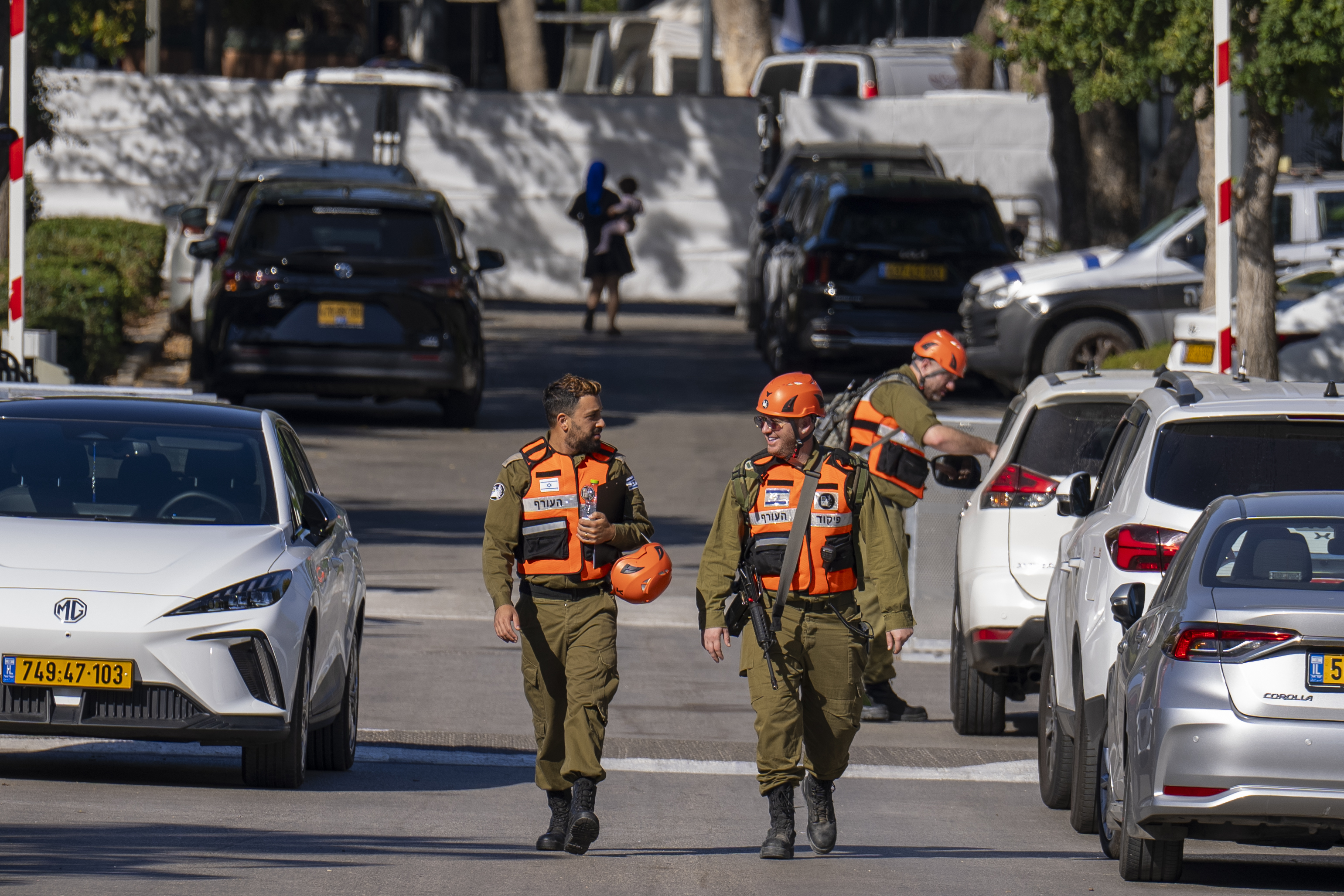 Officers from the Israeli Home Front Command military unit walk on a road near where Israel's government says a drone launched toward Israeli Prime Minister Benjamin Netanyahu's house in Caesarea, Israel, Saturday, Oct. 19, 2024.