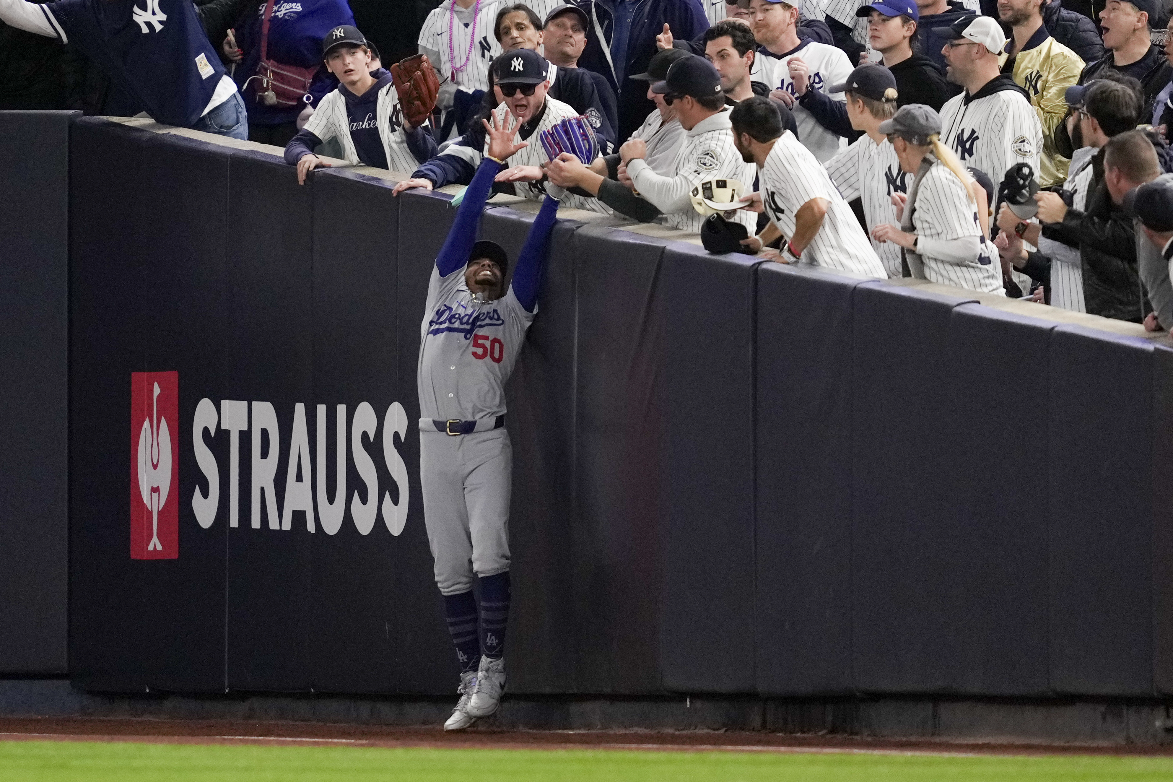 Fans interfere with a foul ball caught by Los Angeles Dodgers right fielder Mookie Betts during the first inning in Game 4 of the baseball World Series against the New York Yankees, Tuesday, Oct. 29, 2024, in New York. (AP Photo/Ashley Landis)