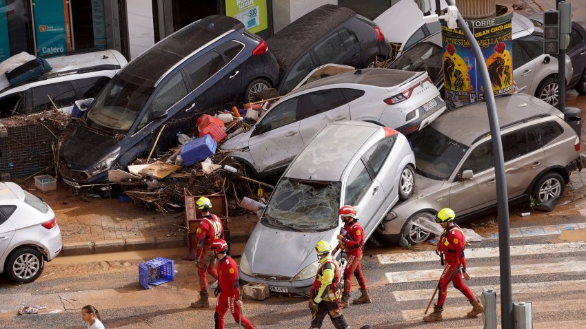 Emergency crew members walk past cars piled up after being swept away by floods in Valencia, Spain, Wednesday, Oct. 30, 2024.