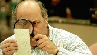 Judge Robert Rosenberg of the Broward County Canvassing Board uses a magnifying glass to examine a dimpled chad on a punch card ballot on Nov. 24, 2000 during a vote recount in Fort Lauderdale, Fla.