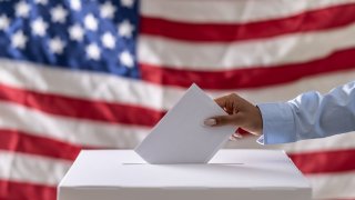 View of hand placing ballot in ballot box