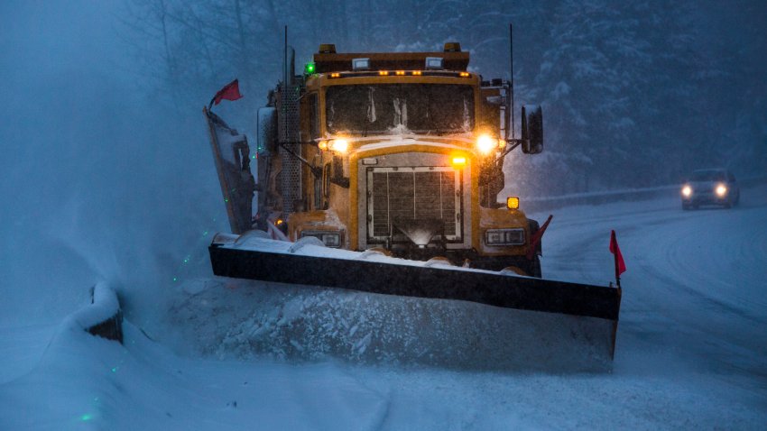 Truck plowing snow off the road at night.