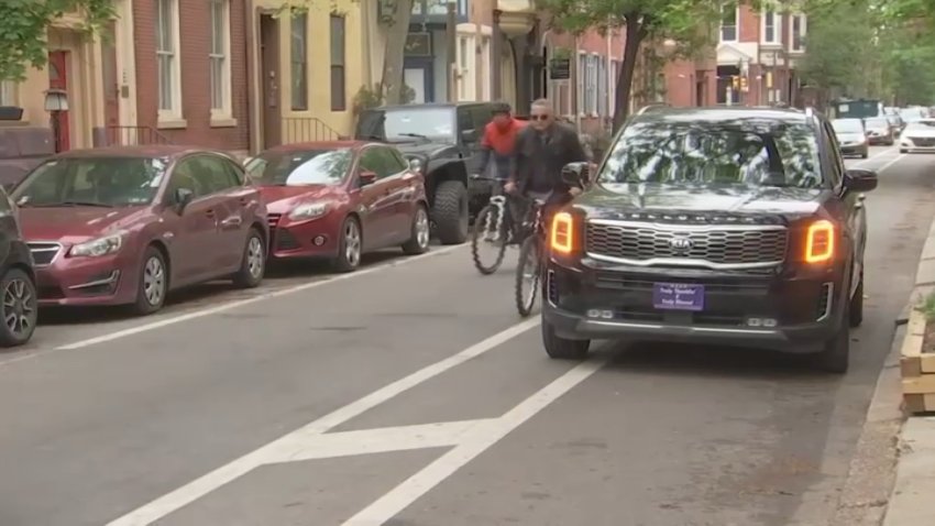 SUV parked in bike lane with cyclists trying to pass.