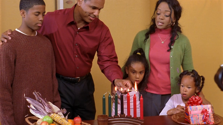 Black family lights Kwanzaa candles