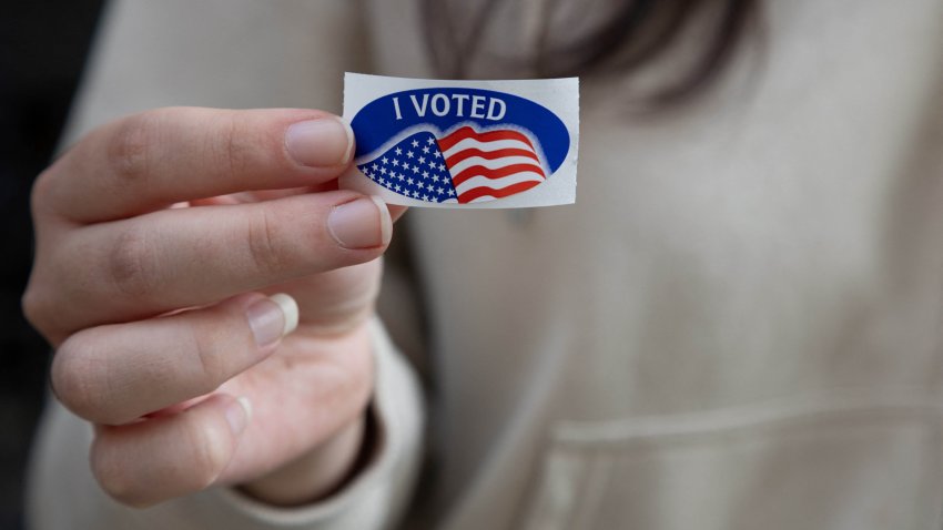 A woman shows off her "I Voted" sticker