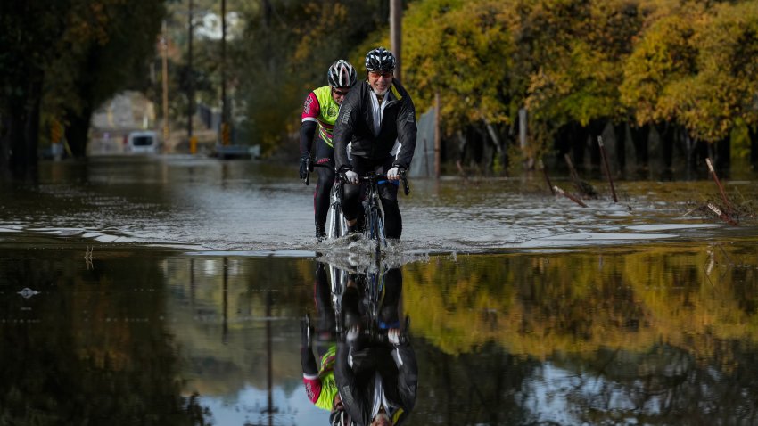 Dave Edmonds, right, and Mike Raasch ride their bicycles on a flooded road