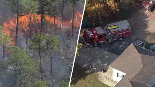 Fire in wooded area and fire truck near Evesham Township home.