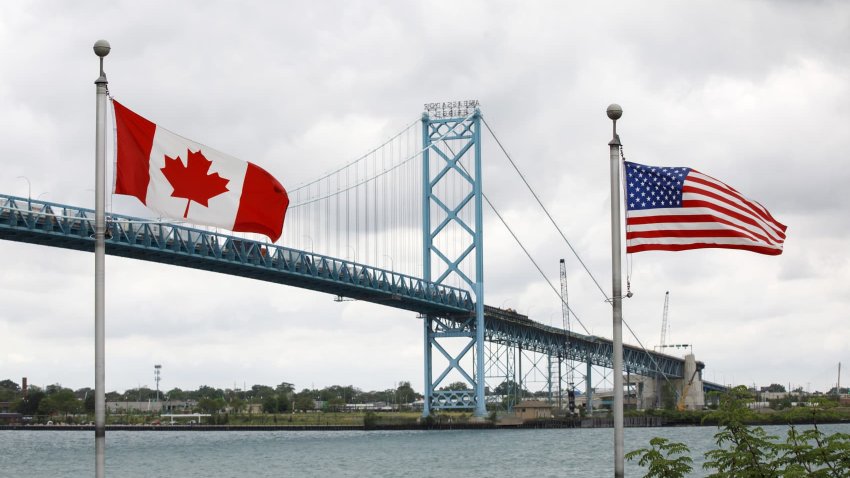 Canadian and American flags fly near the base of the Ambassador Bridge connecting Canada to the U.S. in Windsor, Ontario, Canada, on Wednesday, May 26, 2021.