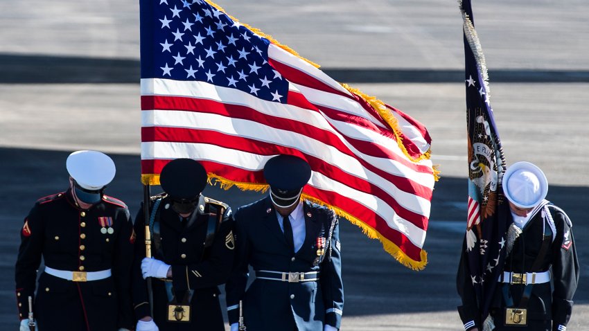 Military flag bearers bow their heads