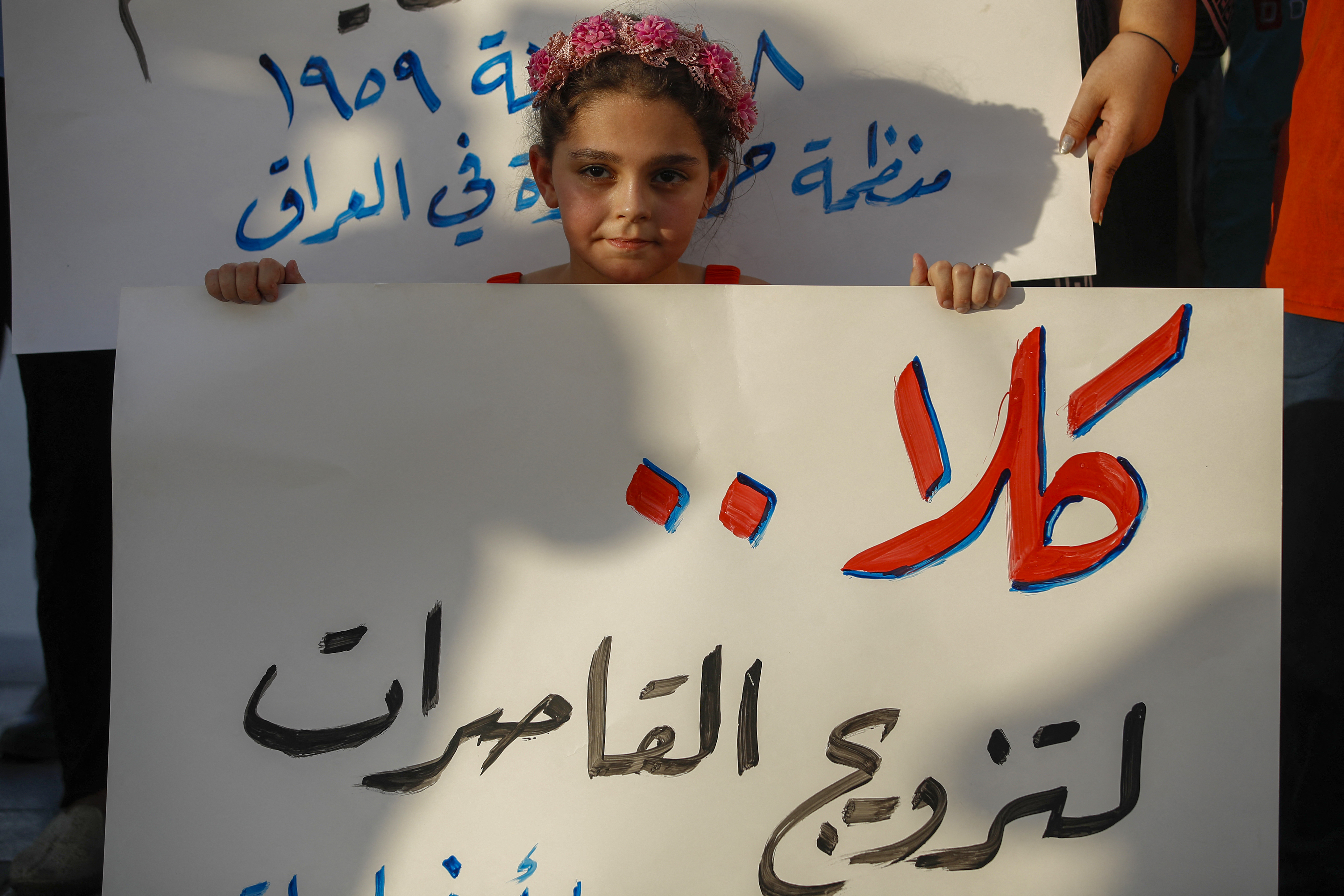 A girl holds a placard as activists demonstrate against female child marriages, in Tahrir Square in central Baghdad on July 28, 2024, amid parliamentary discussion over a proposed amendment to the Iraqi Personal Status Law. Rights advocates are alarmed by a bill introduced to Iraq's parliament that, they fear, would roll back women's rights and increase underage marriage in the deeply patriarchal society. (Photo by AHMAD AL-RUBAYE / AFP) (Photo by AHMAD AL-RUBAYE/AFP via Getty Images)