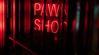 A Neon Sign Saying Pawn Shop Viewed Through The Window Of A Door