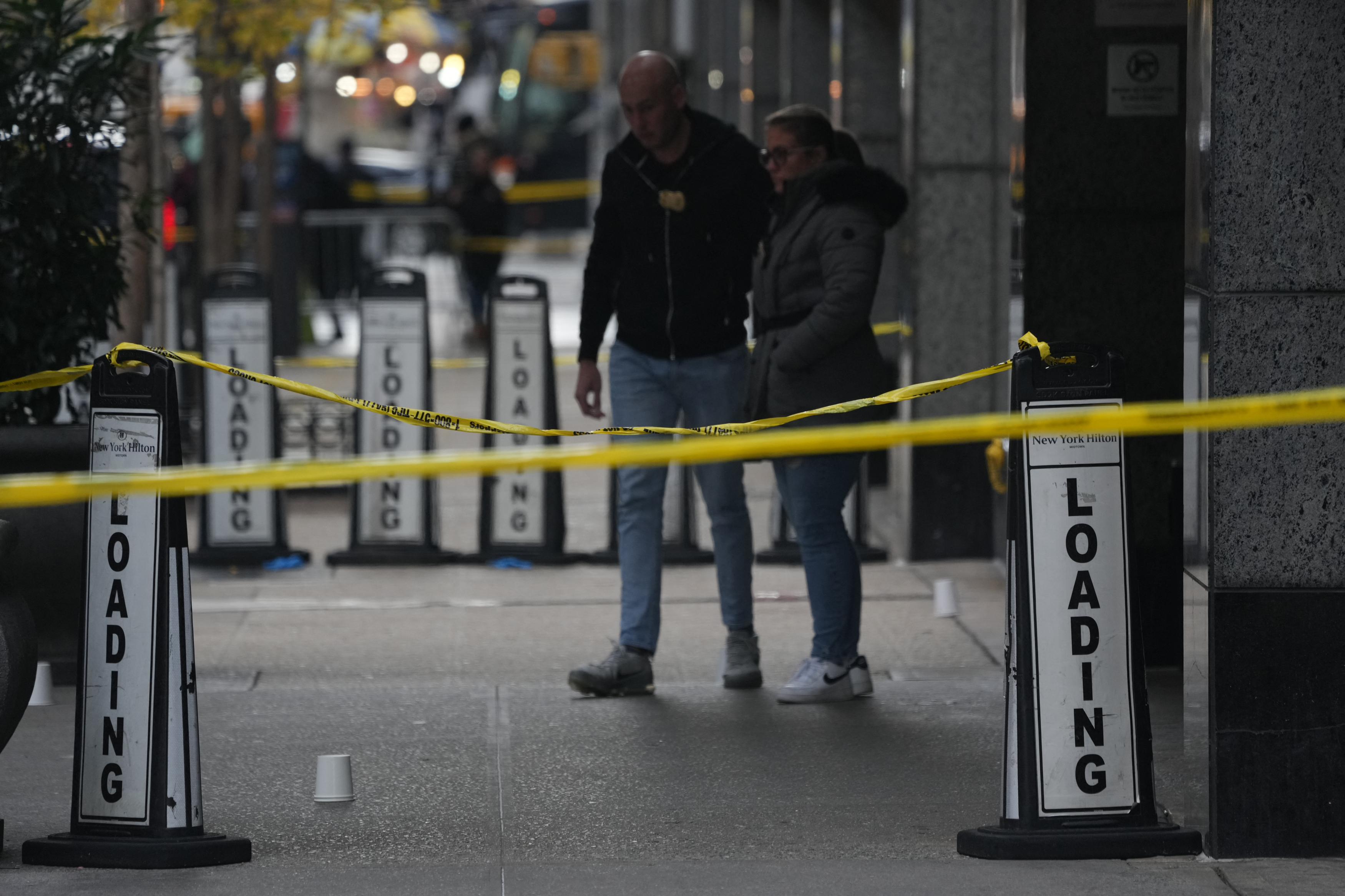 Police cover evidence with paper cups as as CEO of UnitedHealthcare Brian Thompson, 50, was shot as he entered the New York Hilton after 6:45am on December 4, 2024 in New York. The chief executive of one of the United States's largest health insurance companies, UnitedHealthcare, was shot and killed outside a New York Hilton hotel in an apparently targeted hit Wednesday, US media reported. (Photo by Bryan R. SMITH / AFP) (Photo by BRYAN R. SMITH/AFP via Getty Images)