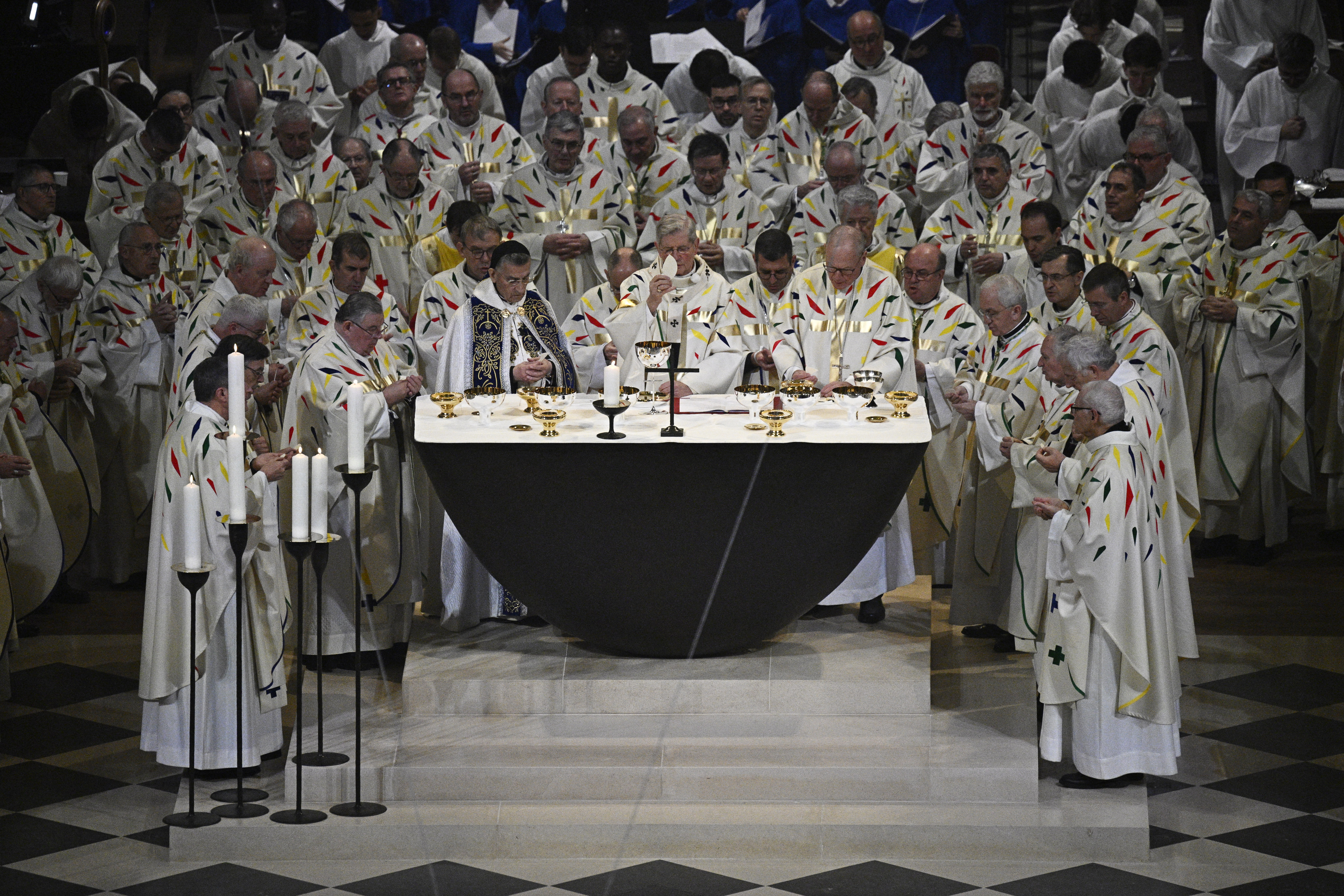 TOPSHOT - The Archbishop of Paris Laurent Ulrich (C) stands amongst prelates as he leads prayers for consecration of the new main altar, designed by French artist and designer Guillaume Bardet which replaces the old one that was destroyed in 2019, during a mass at the Notre-Dame de Paris cathedral, in Paris on December 8, 2024. Newly restored Notre Dame cathedral is set to hold its first service for the public on December 8, 2024 after a historic re-opening ceremony that saw firefighters, builders and artists celebrated for their work saving the 12th-century masterpiece. The beloved Paris monument nearly burned down in 2019, but has been renovated inside and fitted with a new roof and spire during a frenzied reconstruction effort since then. (Photo by JULIEN DE ROSA / AFP) / RESTRICTED TO EDITORIAL USE - MANDATORY MENTION OF THE ARTIST UPON PUBLICATION - TO ILLUSTRATE THE EVENT AS SPECIFIED IN THE CAPTION (Photo by JULIEN DE ROSA/AFP via Getty Images)