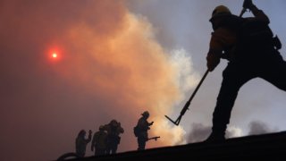 Firefighters work as a brush fire burns in Pacific Palisades, California on Jan. 7, 2025.