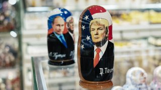 A souvenir shopkeeper displays Matryoshka dolls featuring Russian President Vladimir Putin and U.S. presidents, including Donald Trump.