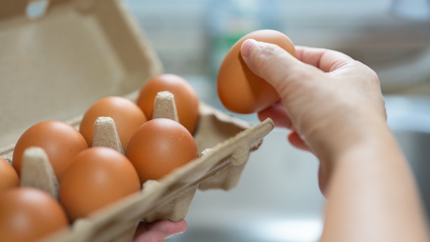 Close up of woman holding a box of fresh organic free range eggs in kitchen. Healthy eating lifestyle